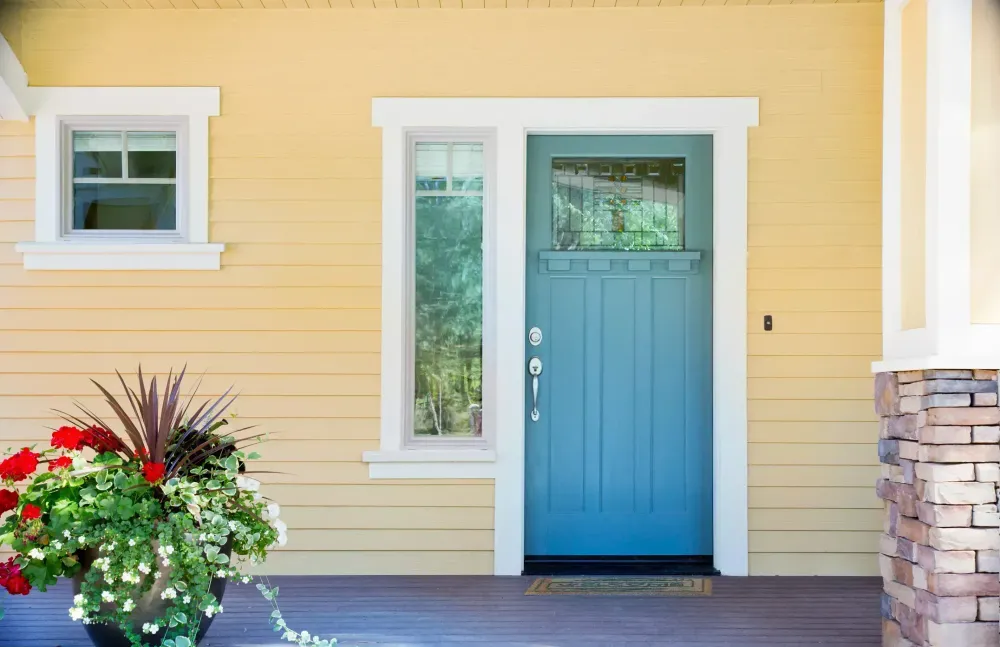 Fachada de casa com paredes em amarelo. As janelas e portas estão da cor azul e contornos brancos.