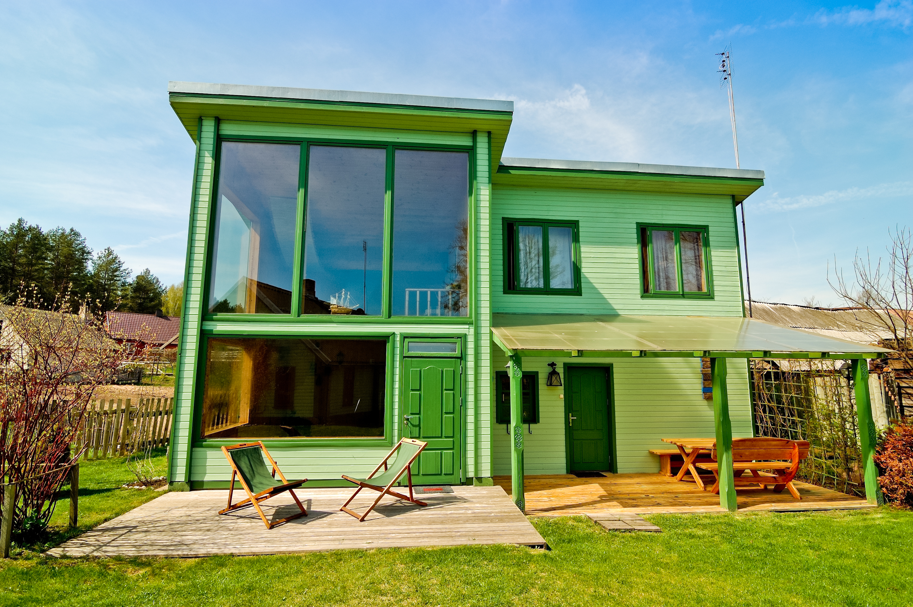 Fachada de casa com tons de verde. Verde claro nas paredes e verde escuro nas portas e janelas.