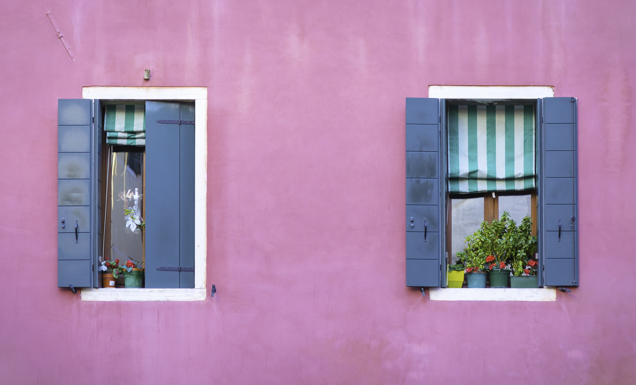 Fachada de casa da cor rosa e janelas azuis.