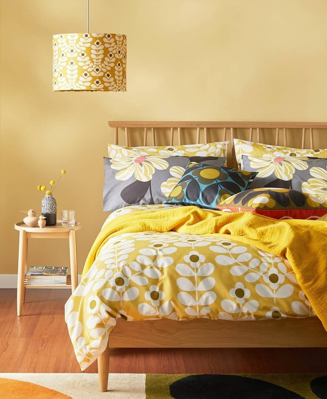 Quarto de casal com parede amarelo bem clara. As roupas de cama também possuem tonalidade amarela.